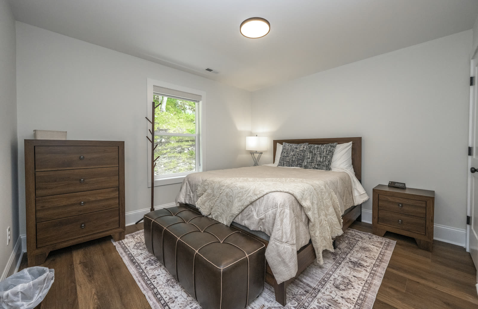 Guest bedroom with wood dresser, dark furniture, and a large window