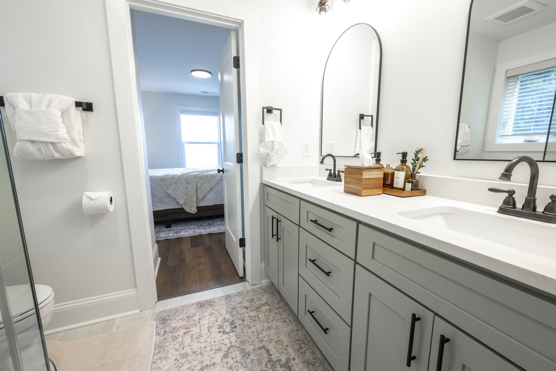Ensuite bathroom with a double vanity, quartz countertop, and arched mirrors