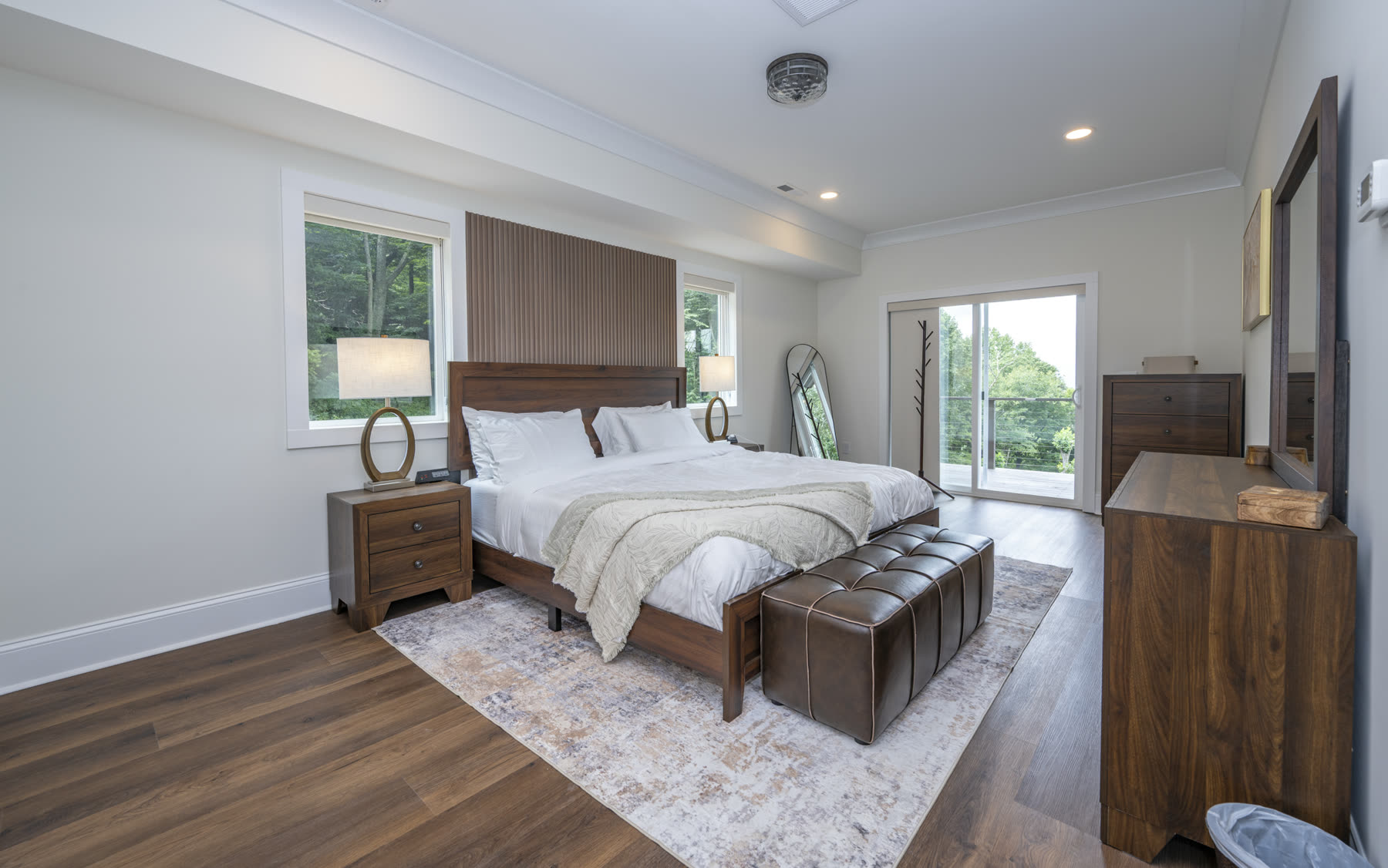 Primary bedroom with wood bed frame, sliding glass doors, and a private balcony overlooking the mountains