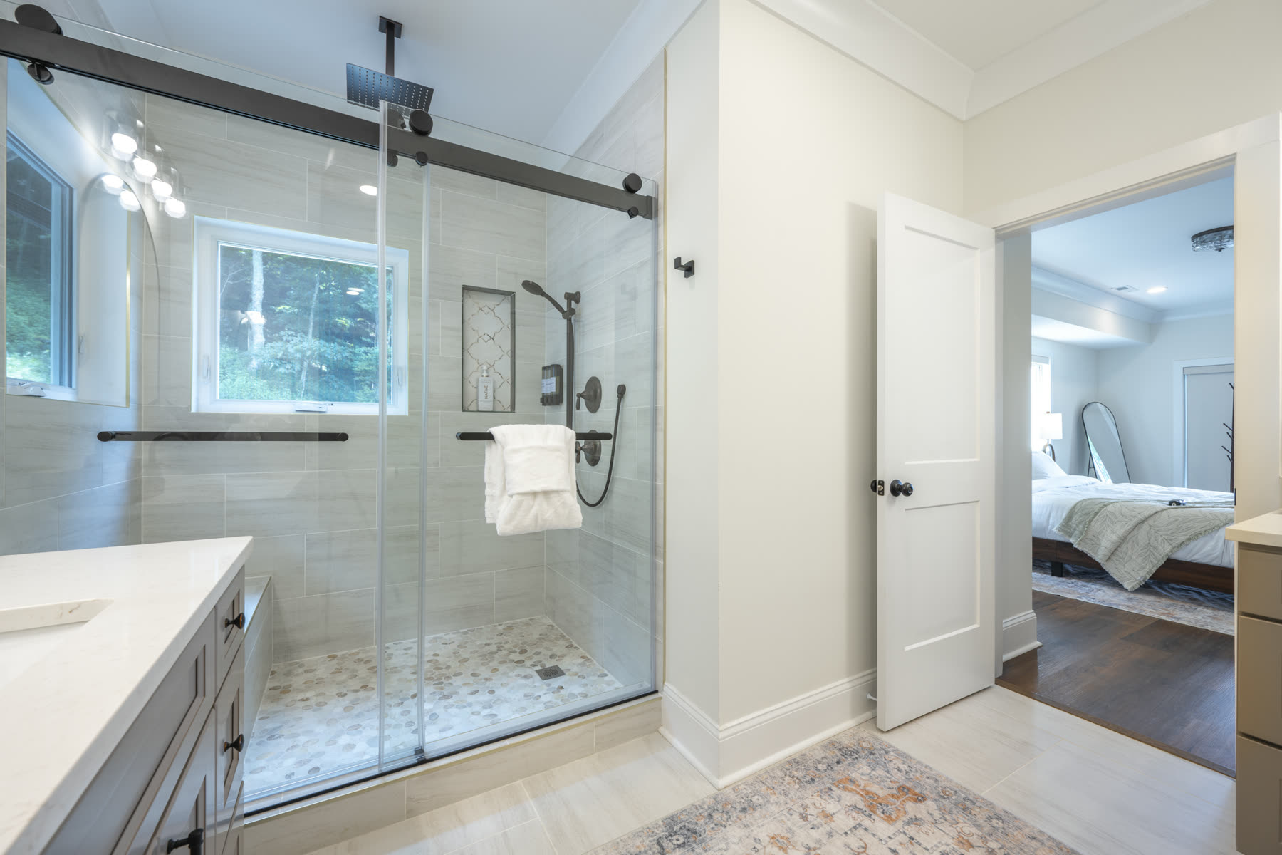 Spa bathroom with a large glass-enclosed tiled shower and window overlooking trees